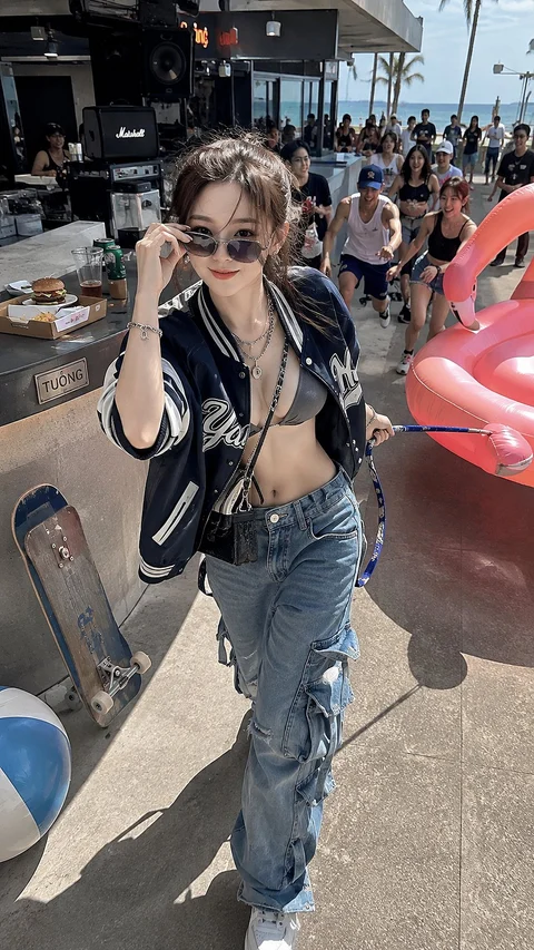 A woman in sunglasses, a dark leather jacket and jeans poses beside cars and a crowd at an outdoor event.